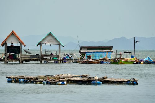 Free Colorful fishing village with huts and boats on a peaceful waterfront setting. Stock Photo