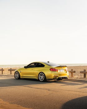 A sleek yellow luxury car parked by the beach during a golden sunset, showcasing elegance and travel vibes.