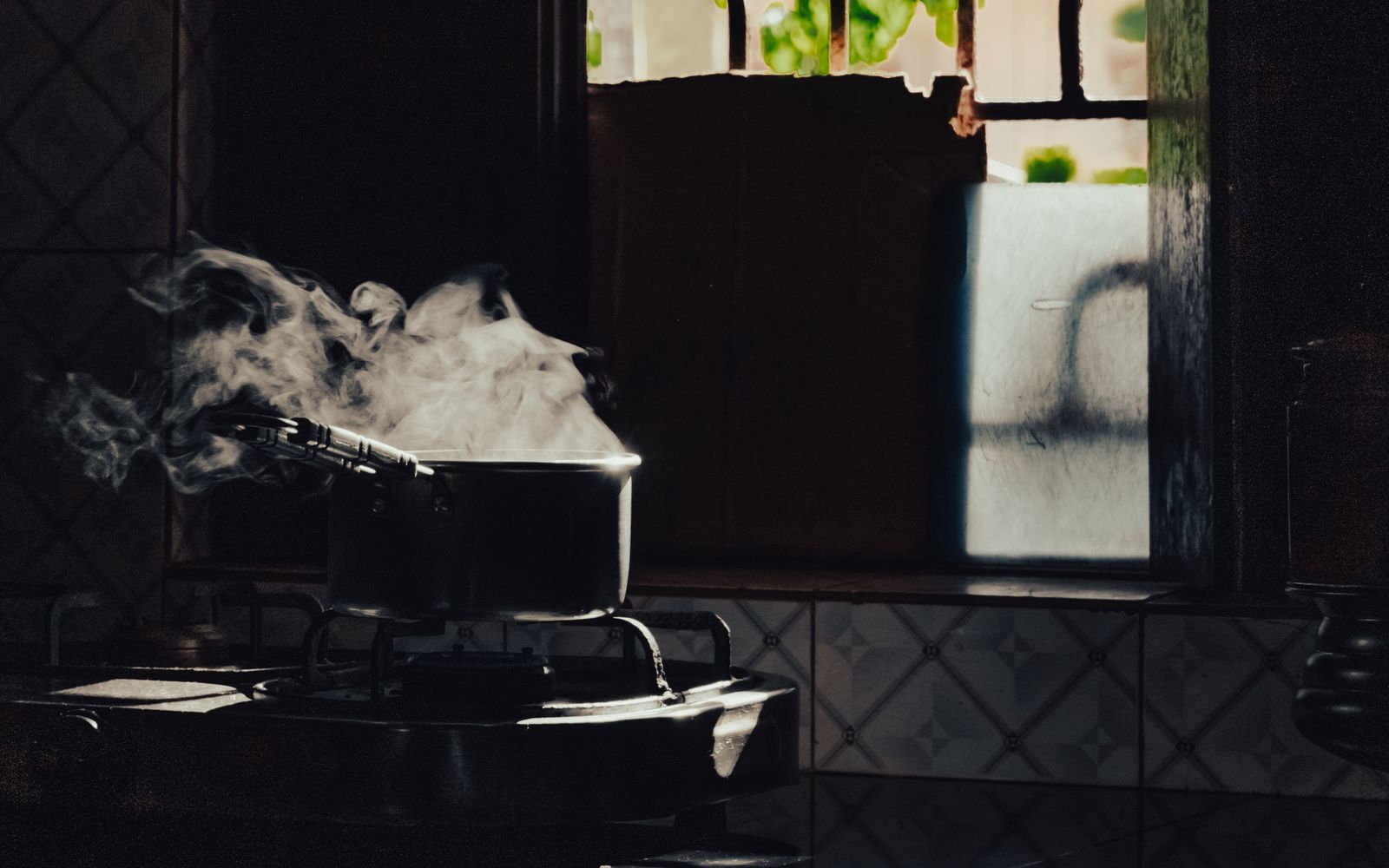 Steam rising from a pot on a stove in a softly lit kitchen