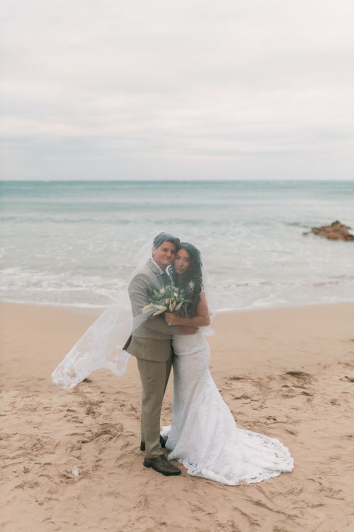Free Bride and groom embracing on a sandy beach, exuding love and happiness. Stock Photo