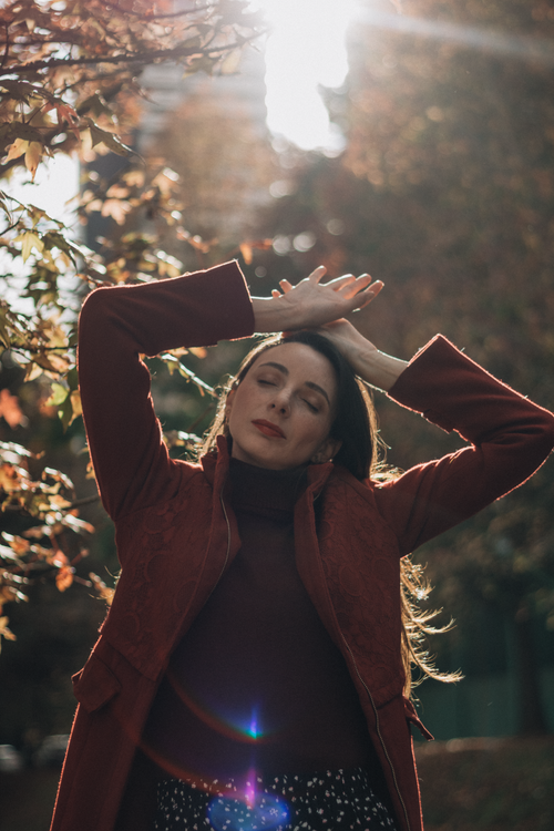 Free Portrait of a woman in autumn sunlight, relaxed pose with fall foliage. Stock Photo