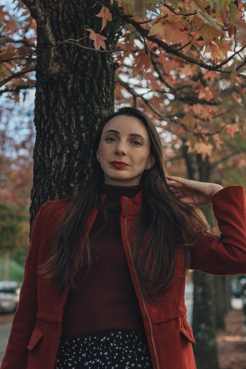 Free Portrait of a woman in a red coat enjoying the autumn scenery outdoors. Stock Photo