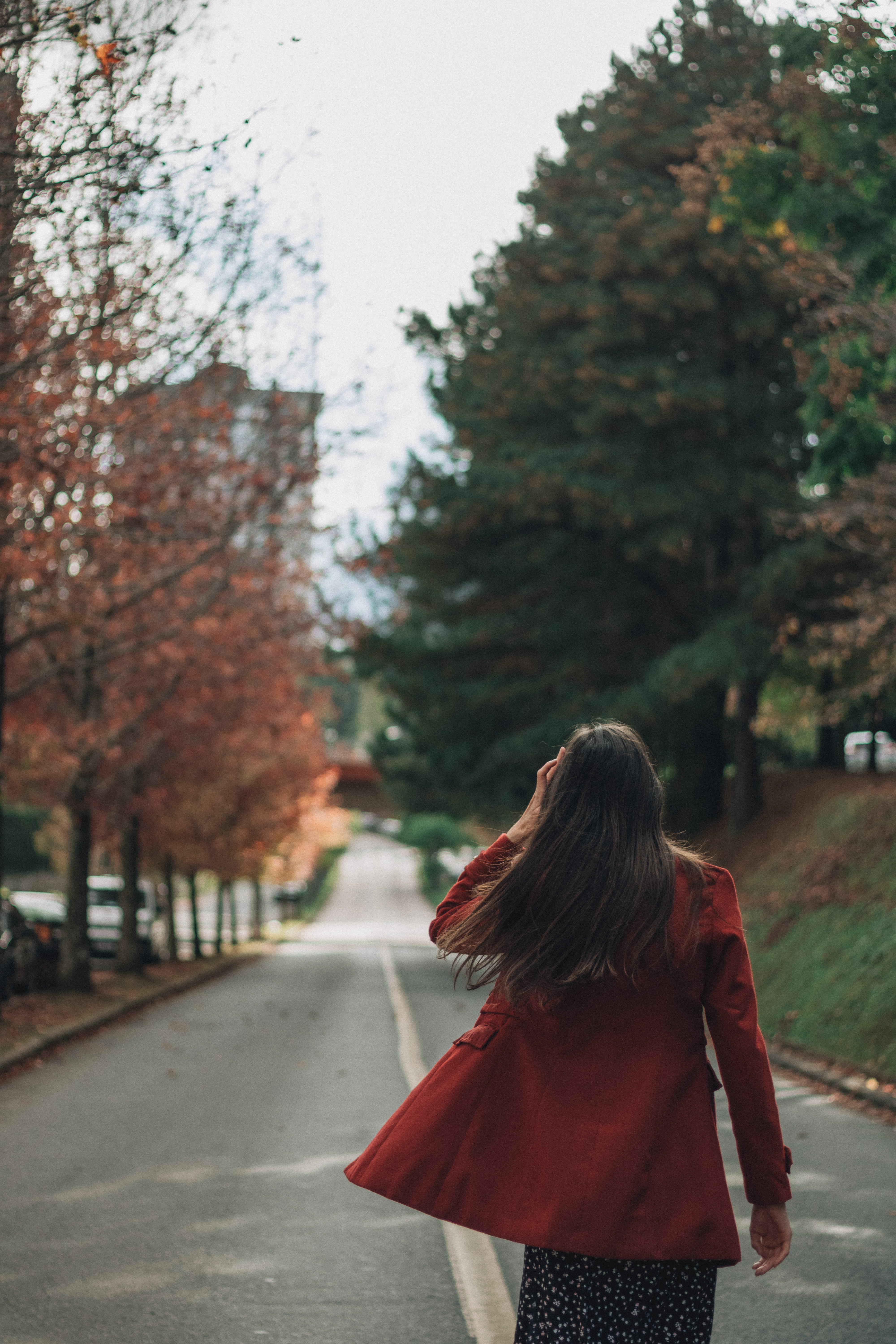 Woman in Red Coat Strolling on Autumn Road · Free Stock Photo