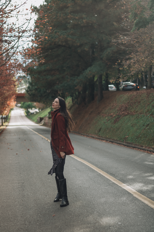 Free Woman enjoying a peaceful moment on a picturesque tree-lined road in autumn scenery. Stock Photo