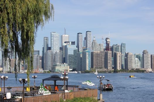 Beautiful view of Toronto skyline from waterfront with boats and greenery.