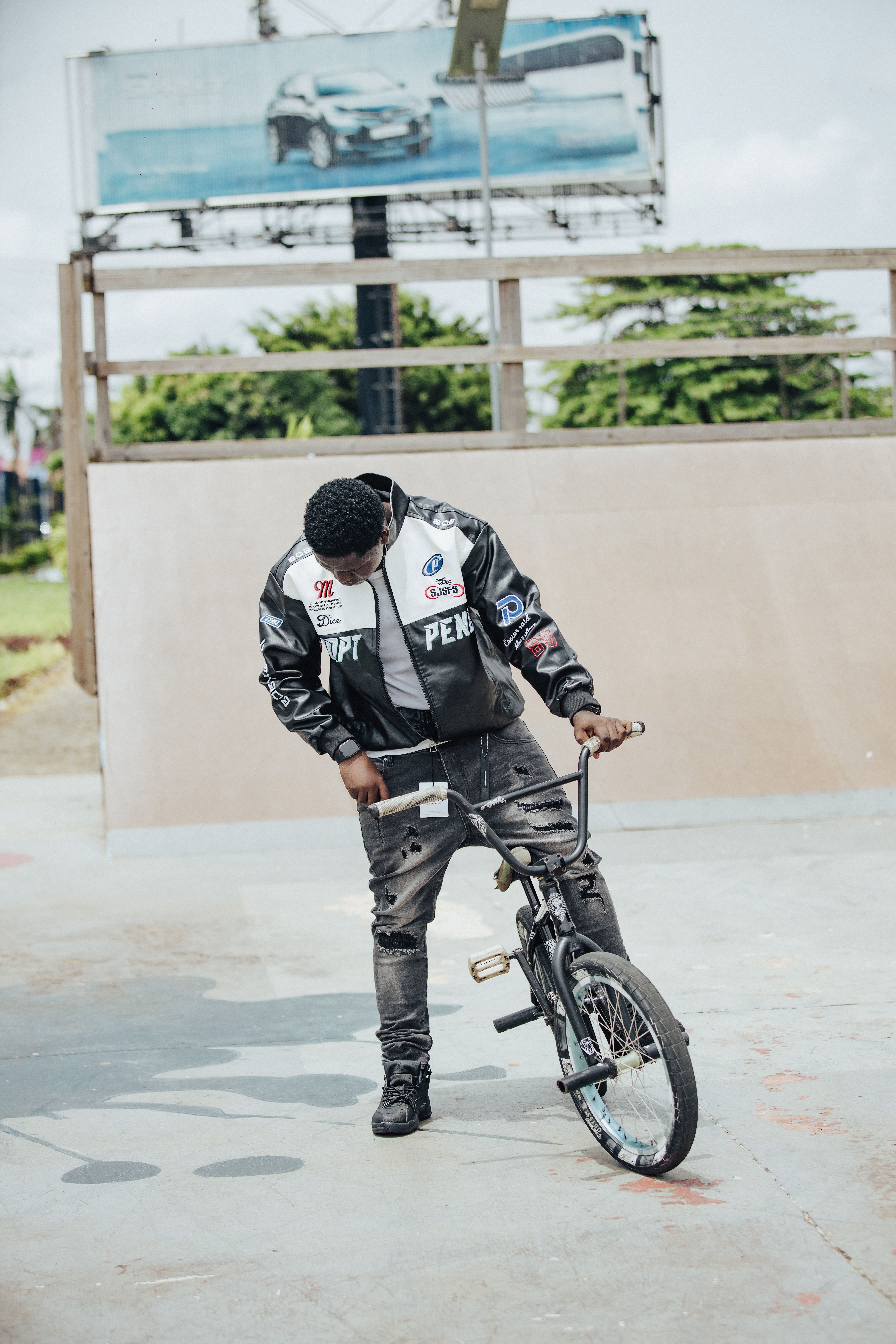 A young adult adjusting his BMX bike at a vibrant outdoor skate park area.