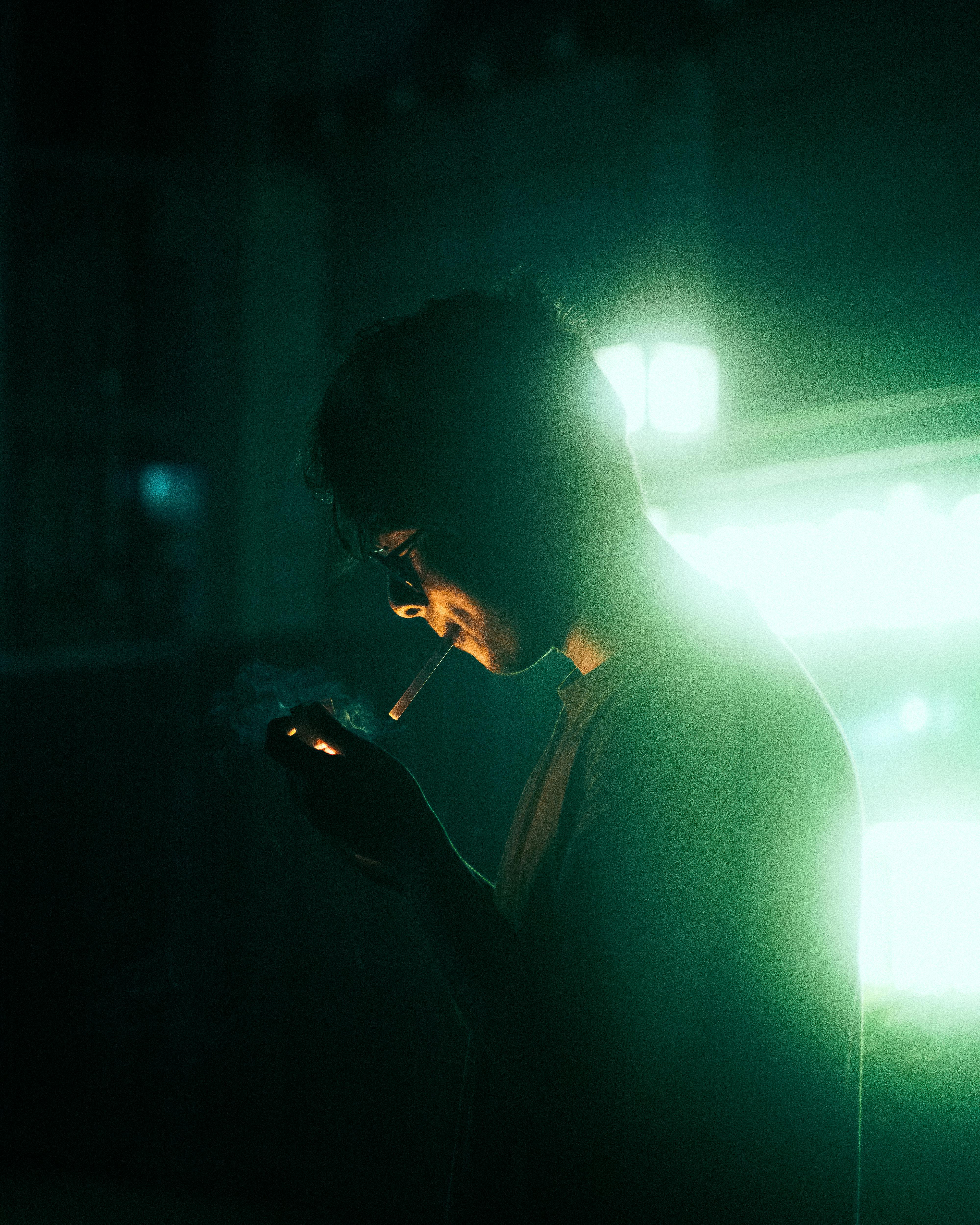 De franc Un home fumant sota una il·luminació dramàtica a la nit amb una atmosfera malhumorada. Foto d'estoc