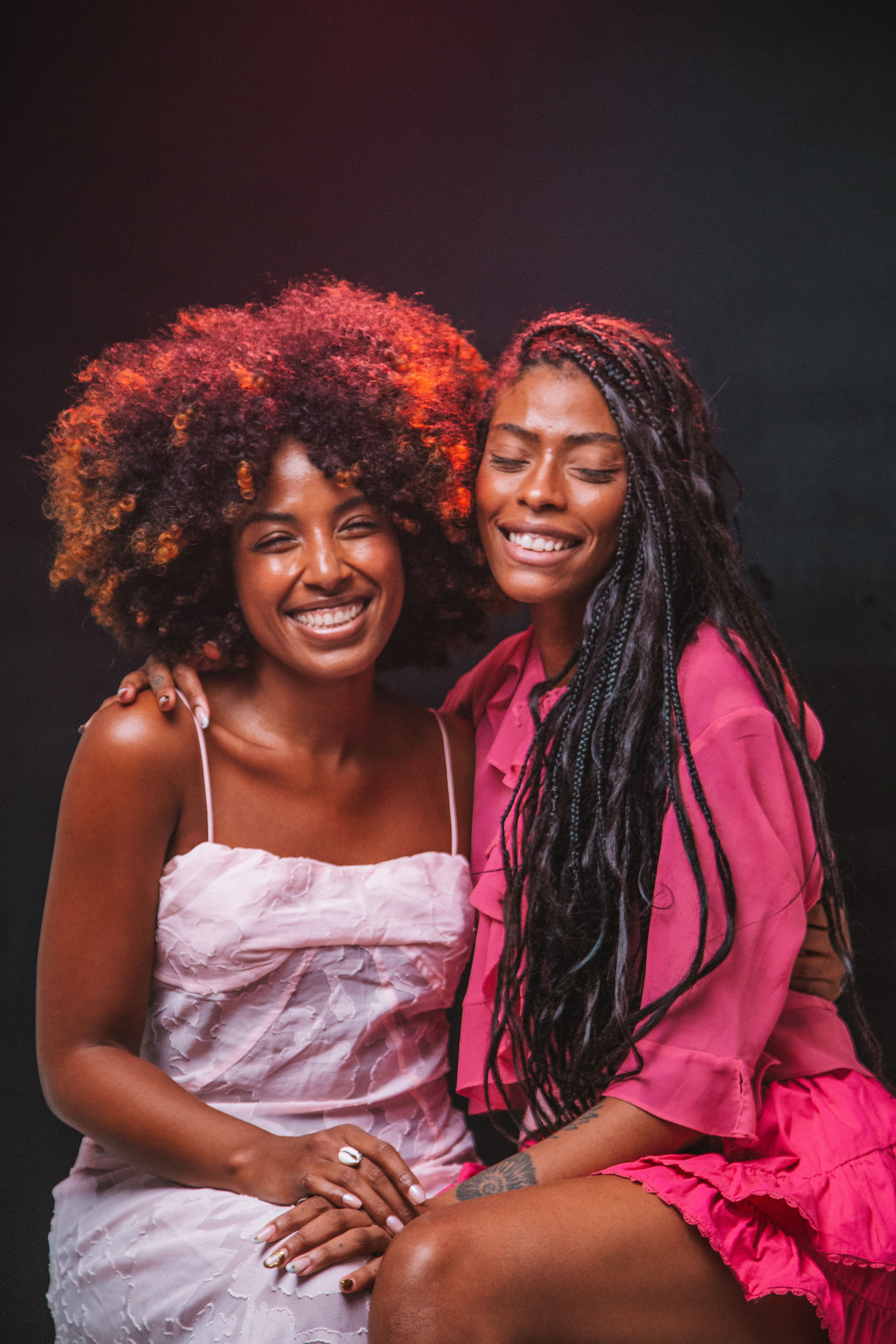 Two joyful African American women smiling and embracing, showing strong friendship and happiness.