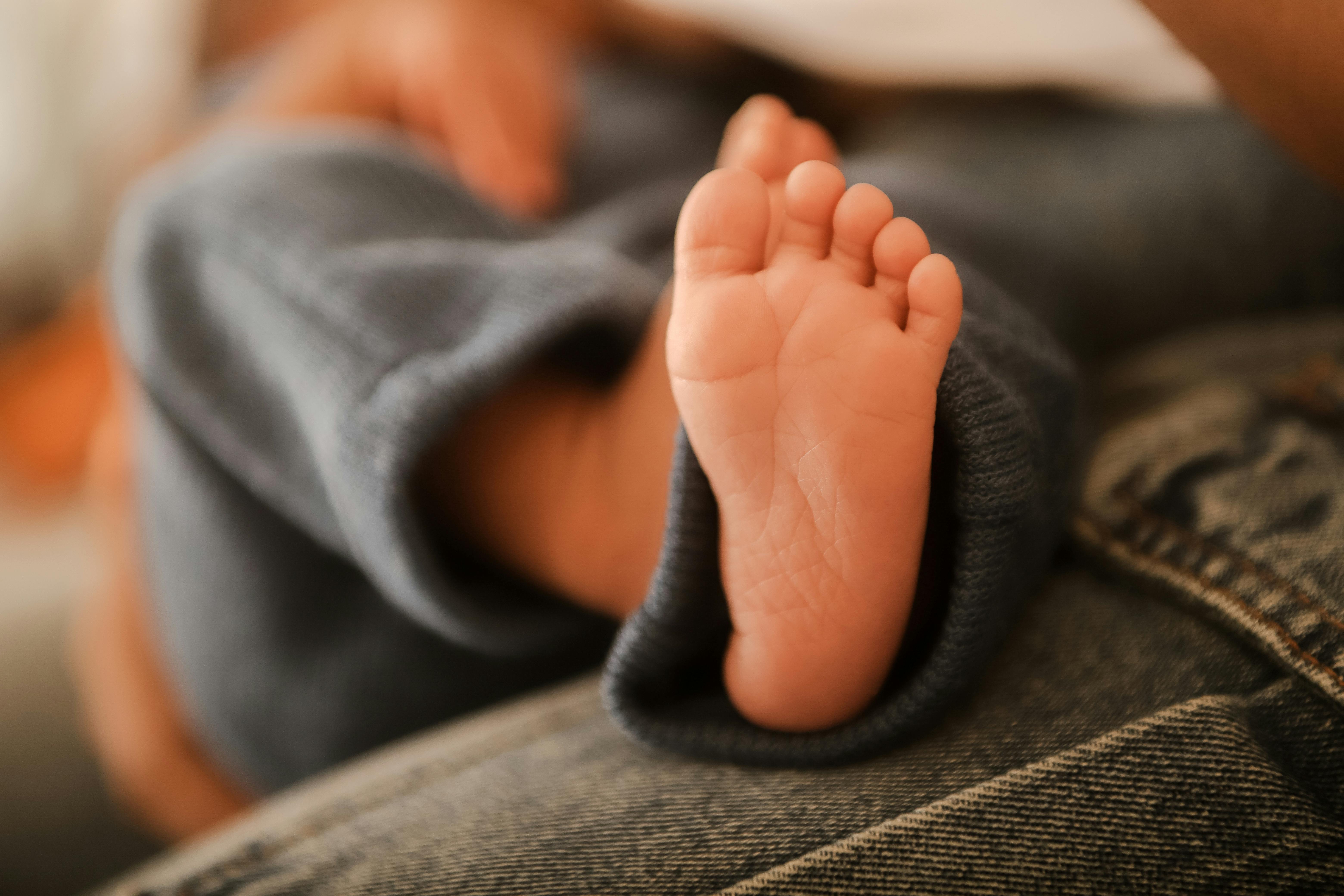 Free A close-up of a newborn baby's foot, softly focused with a warm and cozy atmosphere. Stock Photo