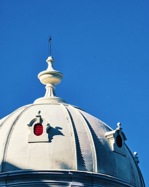 Free Elegant white dome architecture with red windows under a vivid blue sky. Stock Photo