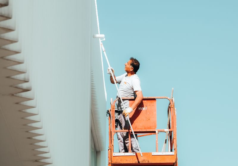 Painter coating a building exterior from an elevated platform