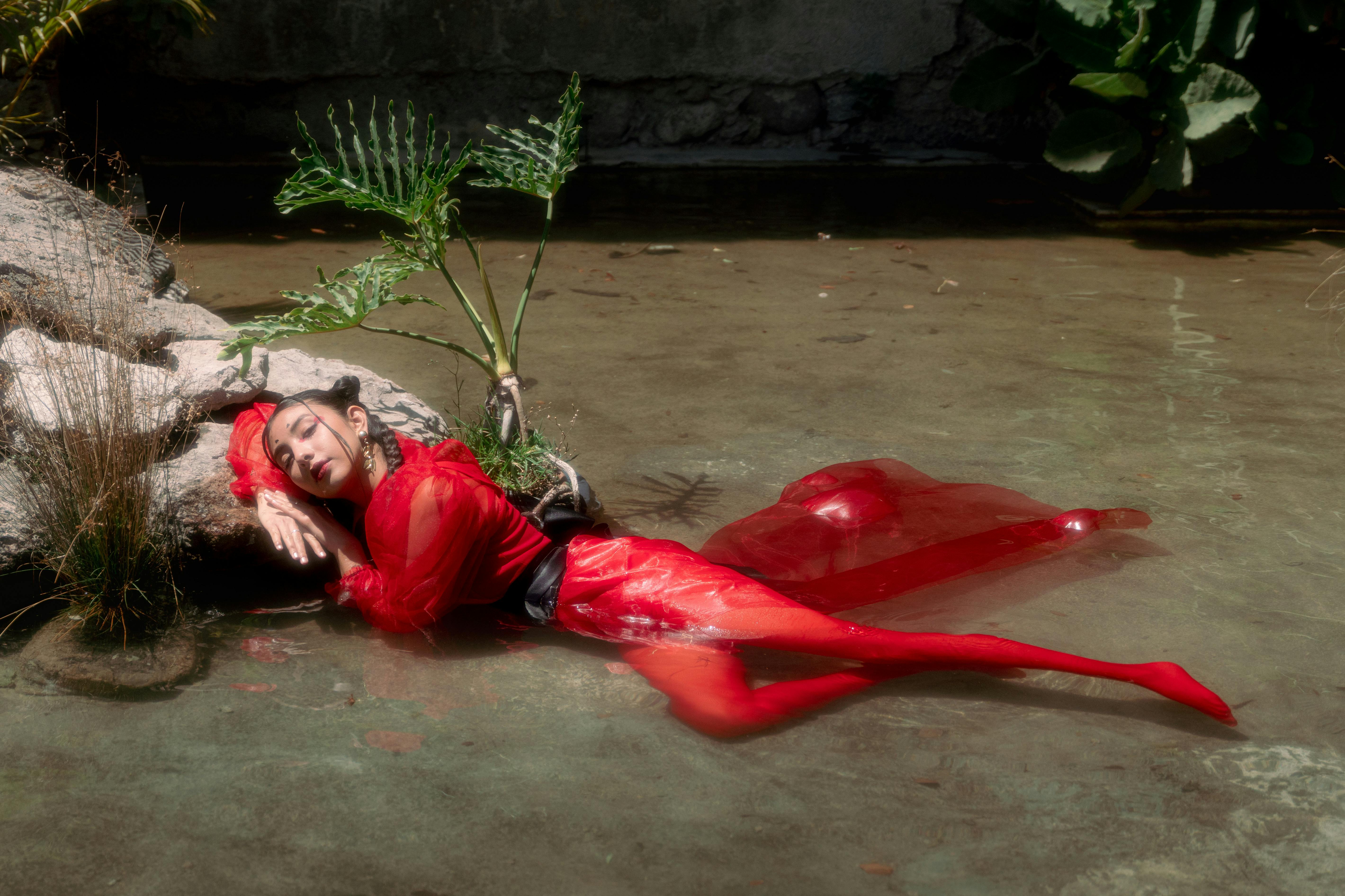 Stunning editorial shot of a model in red by the water, blending style and nature.
