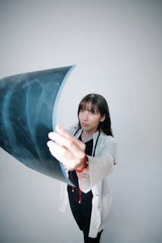 A focused young female doctor examines an X-ray film in a bright clinical setting, demonstrating medical expertise.