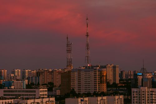 Free A cityscape with tall buildings and antennas under a vibrant pink dusk sky. Stock Photo