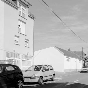 A monochrome street view in Compiègne, France featuring parked cars and residential buildings.