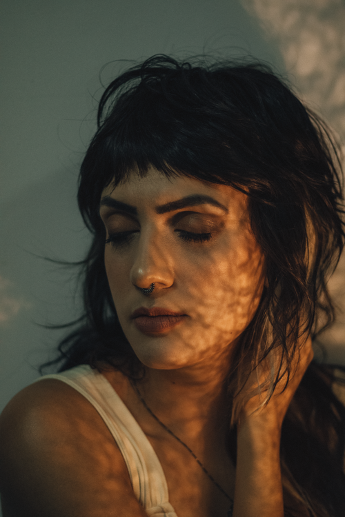 Free Calm woman with closed eyes bathed in artistic shadows indoors. Stock Photo