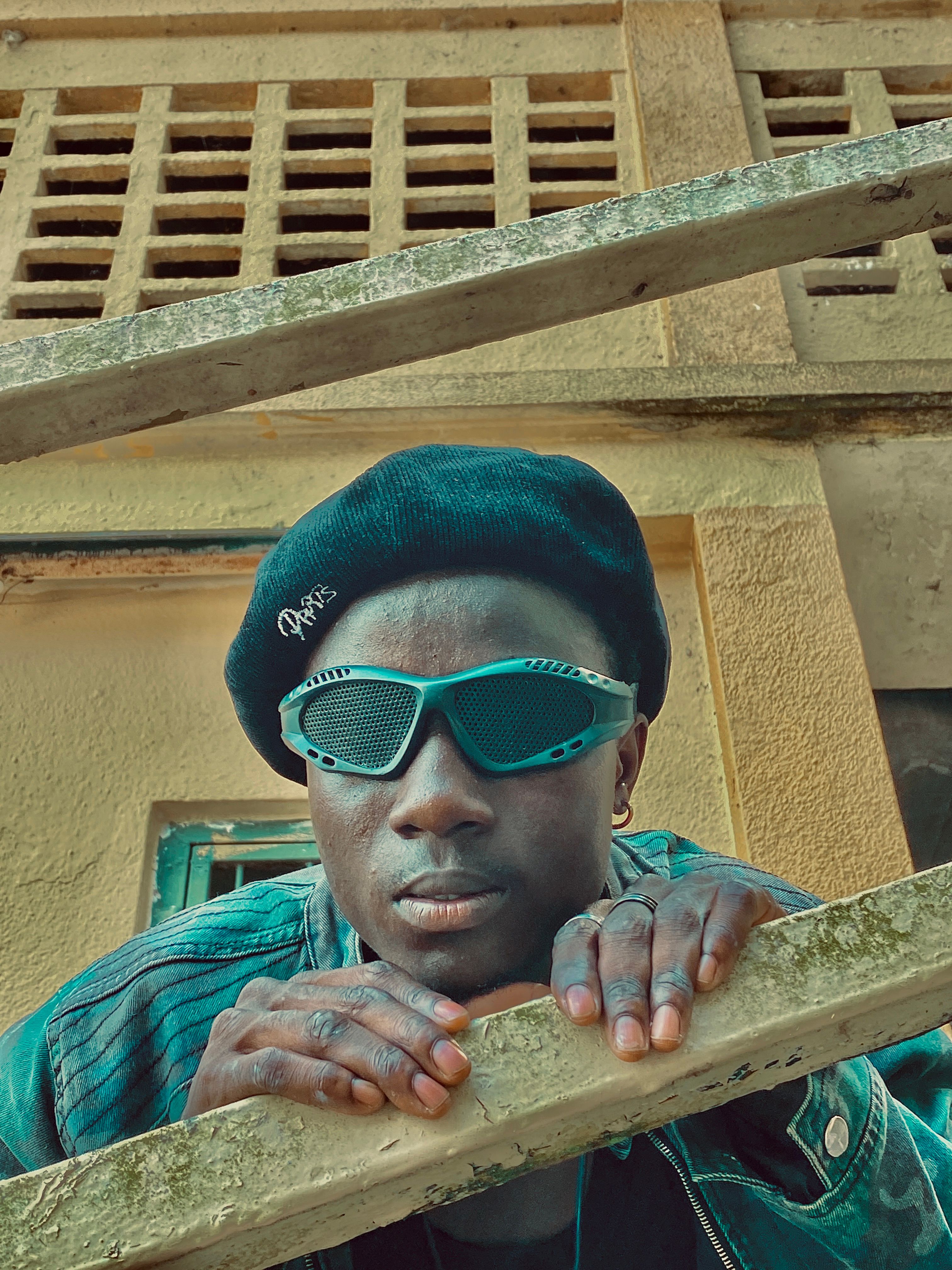 Portrait of a fashionable man wearing a beret and sunglasses, with an urban background.