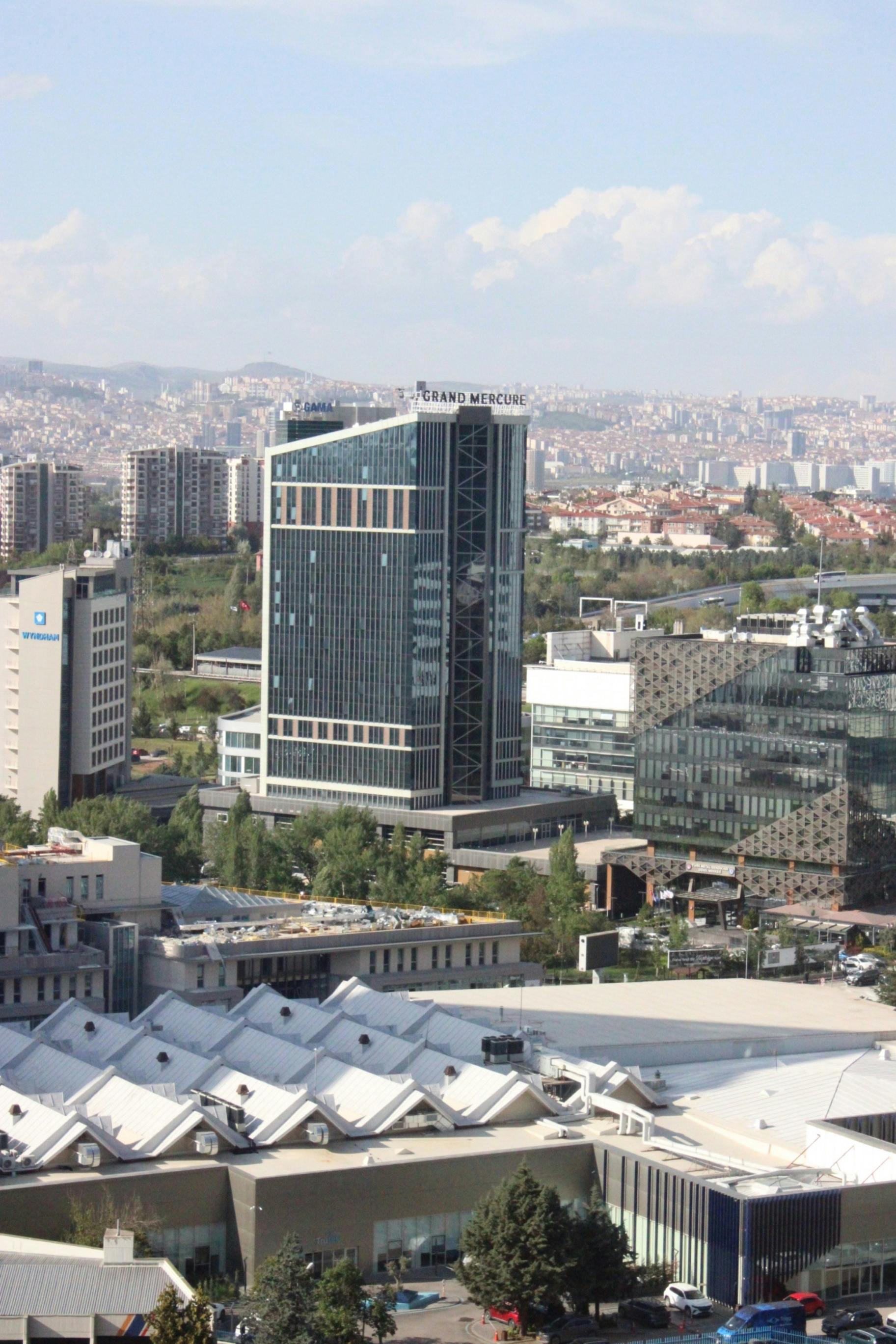 Modern skyscraper amidst cityscape under bright sky in urban area.