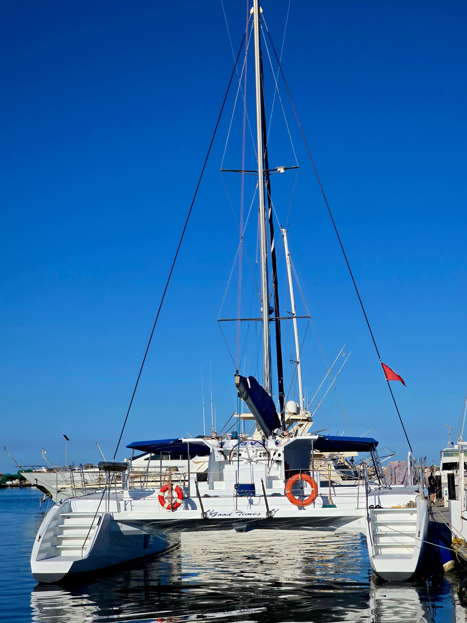 catamaran rental Marbella — Sleek white catamaran docked at a marina under blue sky