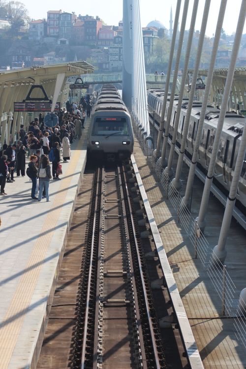 Free A busy train station with a train approaching on a modern bridge, capturing urban transit. Stock Photo