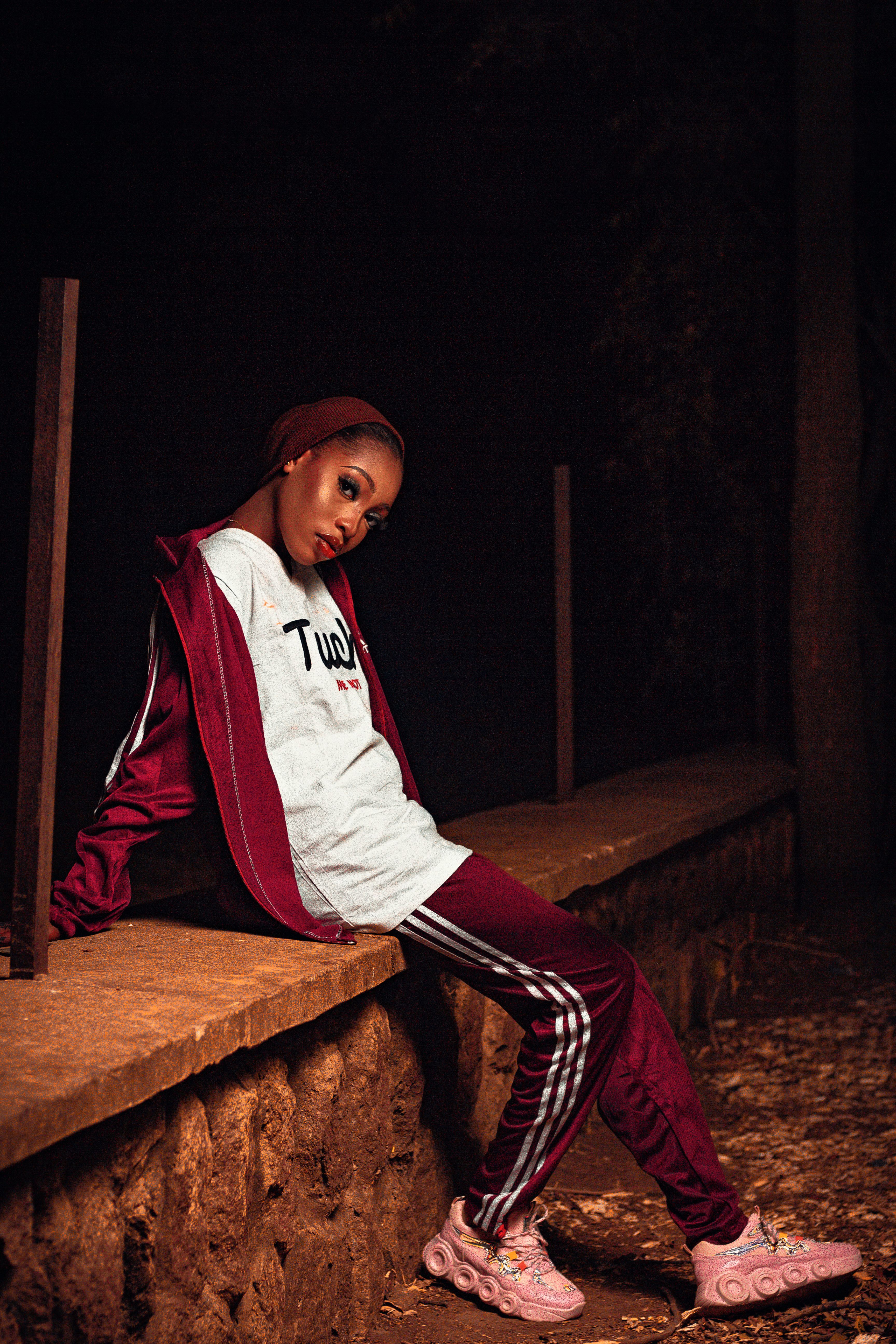 Fashionable woman in a tracksuit posing at night outdoors, showcasing streetwear style with attitude.