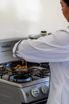 A professional chef prepares a meal on a gas stove in a modern kitchen.