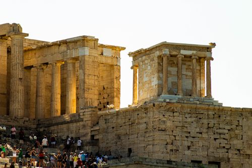 Free View of the ancient Acropolis temple in Athens, Greece with tourists exploring its grandeur. Stock Photo