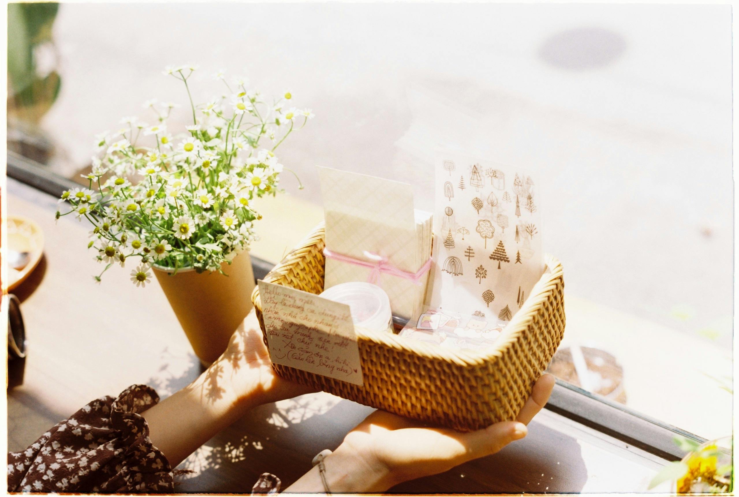 A beautiful gift basket with cards and chamomile flowers on a sunny windowsill.