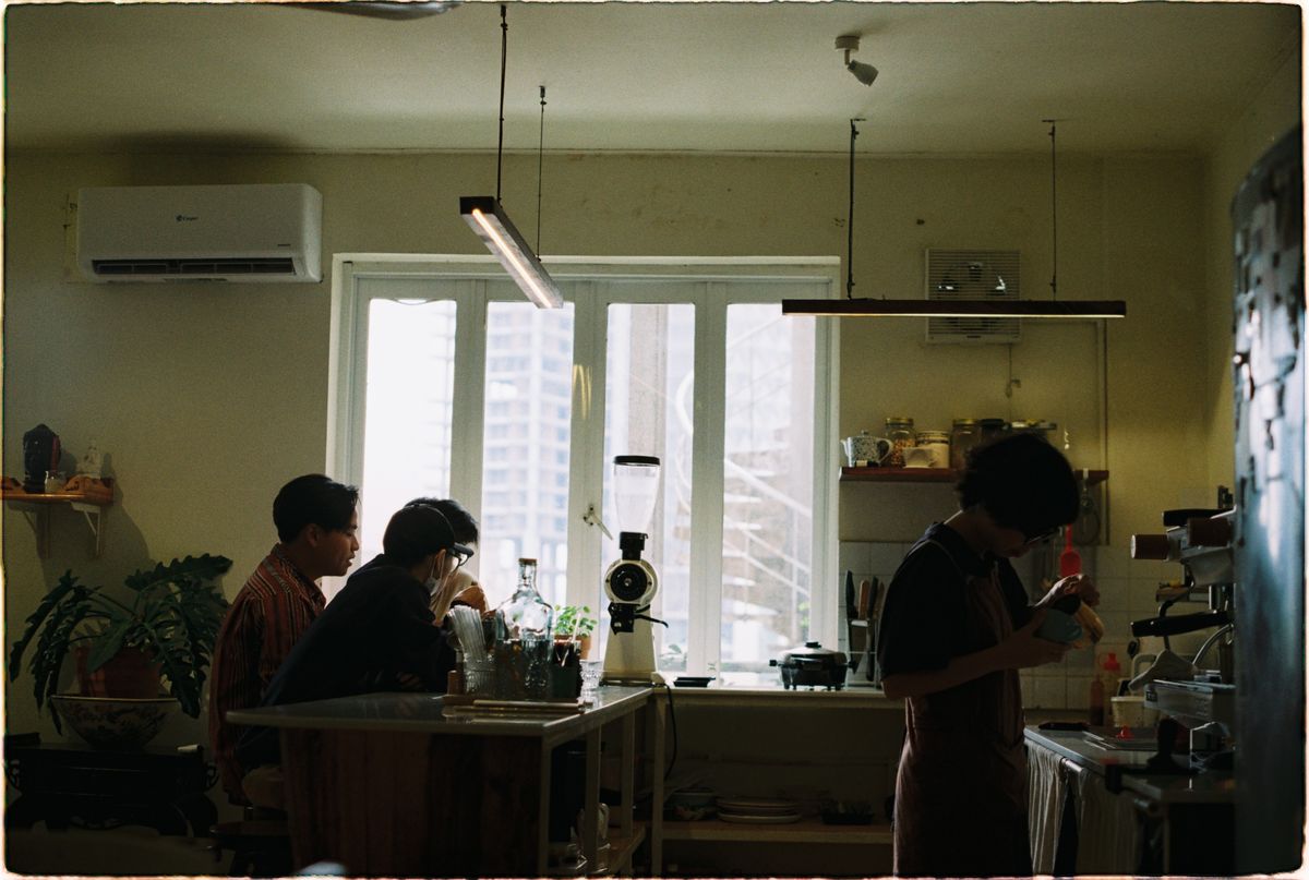 Barista working while customers sit near the window in a quiet coffee shop