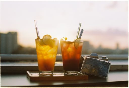 Two iced tea cocktails with lemon slices at sunset, creating a warm and inviting atmosphere.