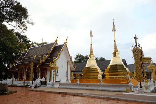 Free Beautiful view of golden stupas at a Thai temple with intricate architecture under a cloudy sky. Stock Photo