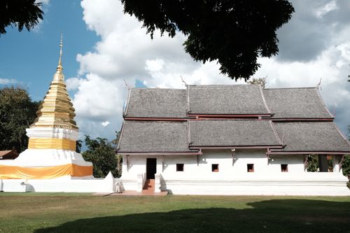 Free A serene view of a historic Buddhist temple and stupa under a bright sky, highlighting traditional architecture. Stock Photo