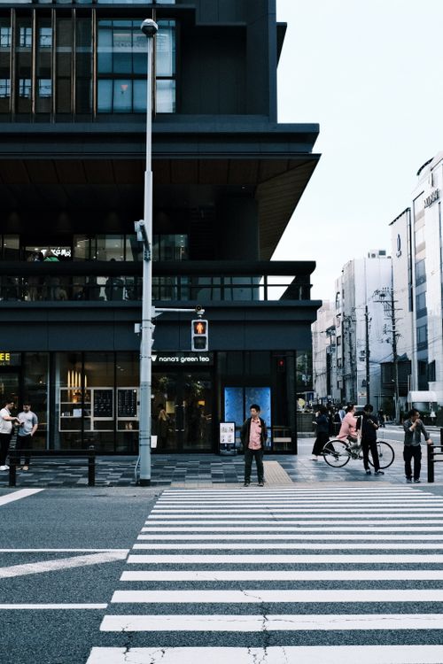 Free City street view with pedestrians at a zebra crossing by modern buildings during dusk. Stock Photo