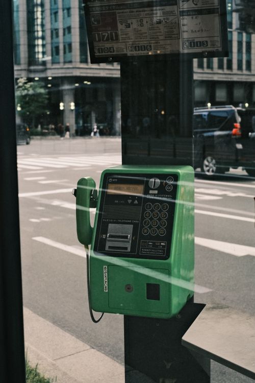 Free A green public payphone against a city street backdrop, reflecting urban nostalgia. Stock Photo