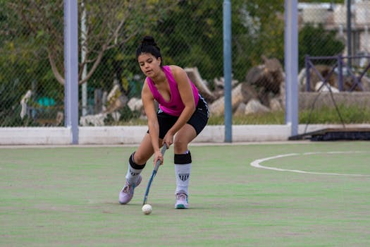 Dynamic shot of a female field hockey player in action outdoors on a green field.