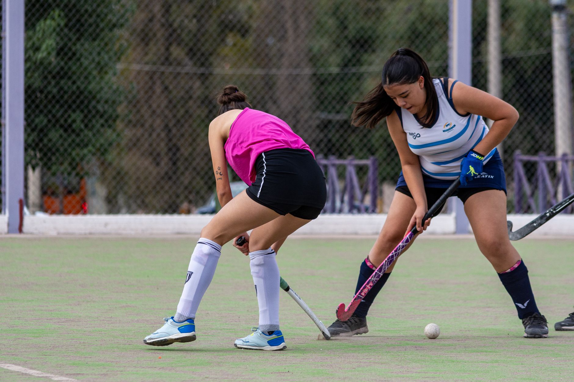 Intense game of field hockey with two women competing on an outdoor court.