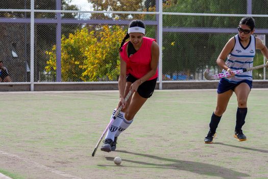 Dynamic field hockey game featuring two female players competing outdoors.