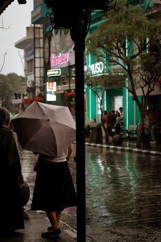 Moody urban street scene with umbrellas in Jawa Barat, Indonesia during rainy season.
