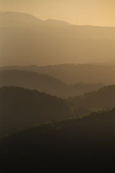Serene layers of hills in Graz at sunset, capturing a tranquil and misty atmosphere.