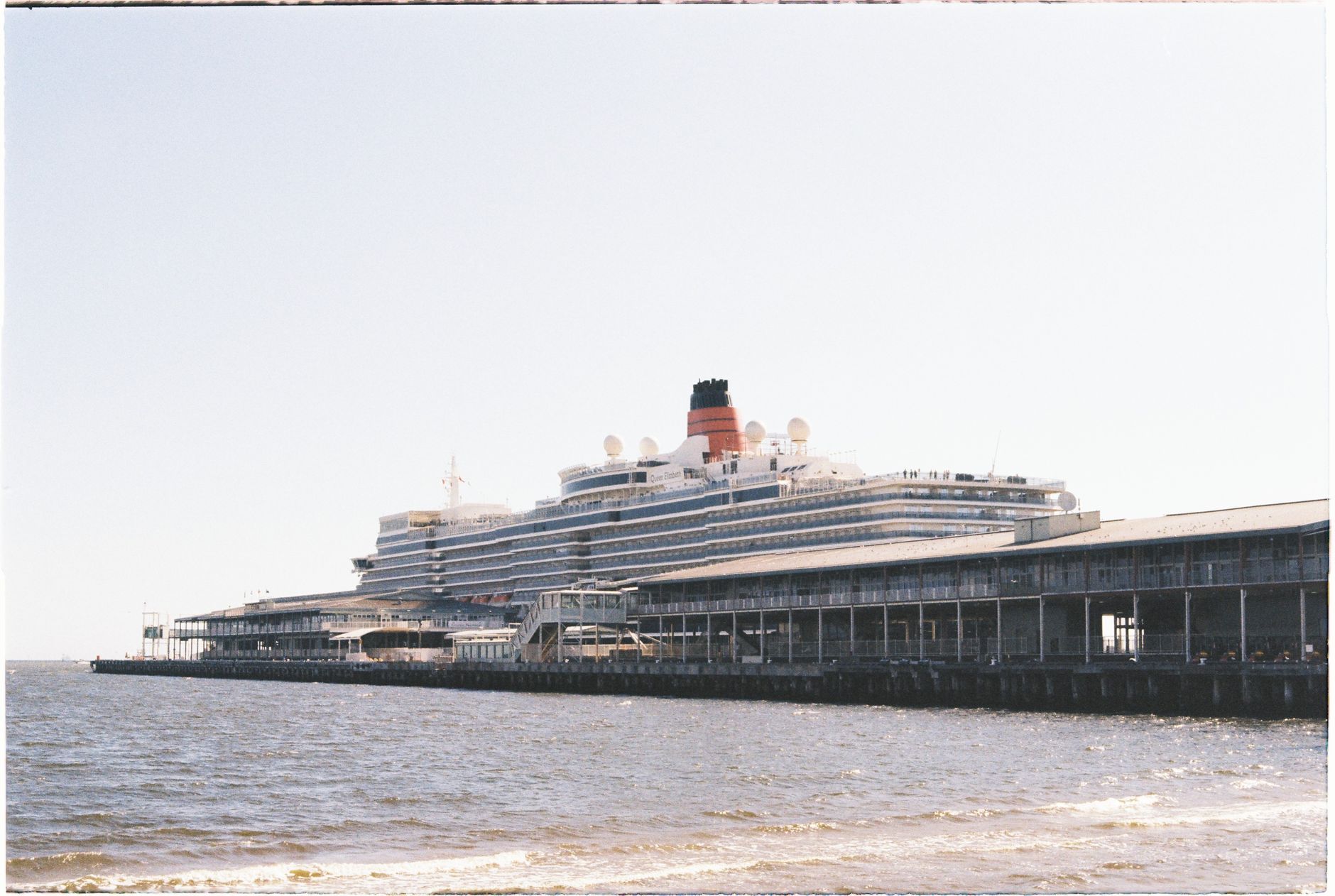 A grand cruise ship docked at the port in Melbourne, Australia under a clear sky.
