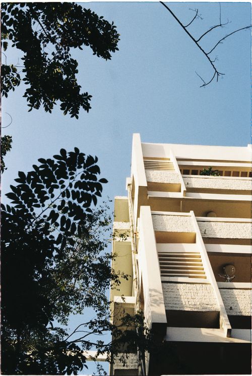 Free A perspective of modernist architecture in Hanoi, adorned with lush foliage against a clear blue sky. Stock Photo