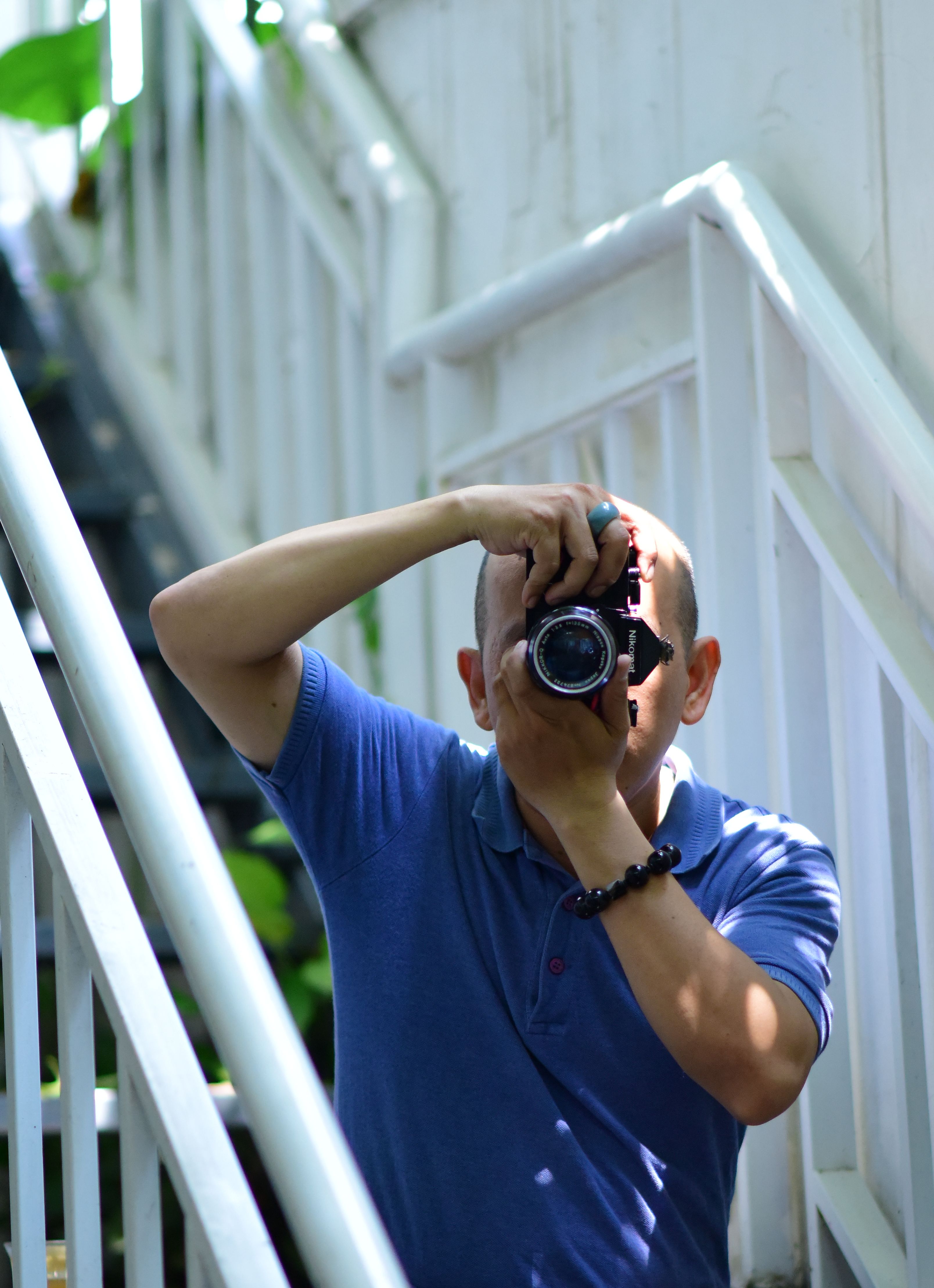 A photographer takes a picture on an outdoor staircase during daylight.