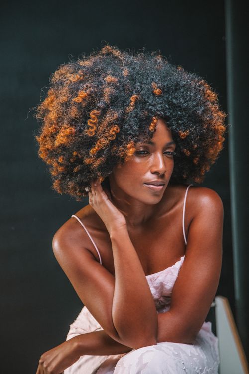 Free Striking portrait of a woman with voluminous curly hair exuding elegance. Stock Photo