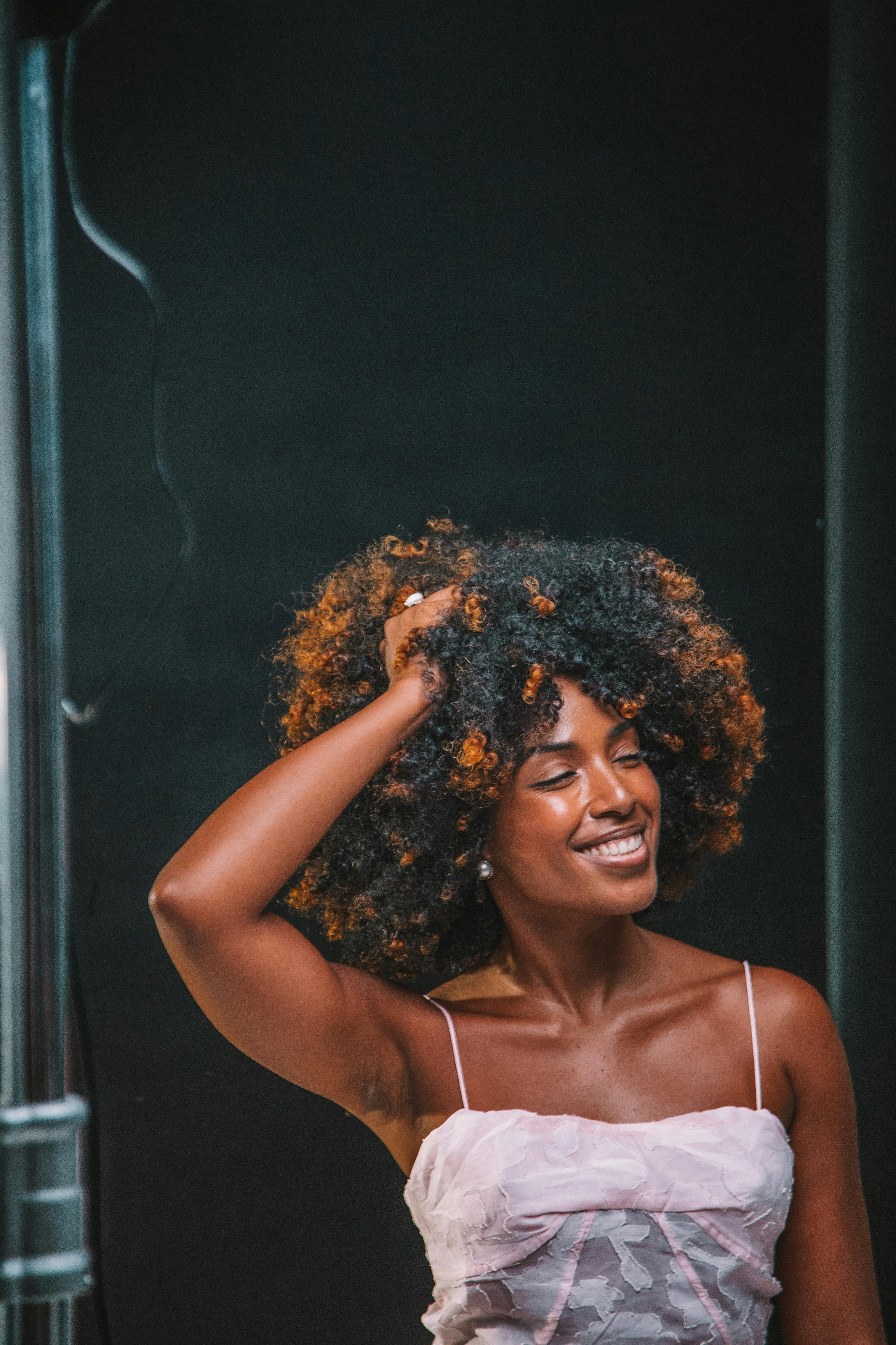 Portrait of a woman with curly hair enjoying a candid moment indoors.