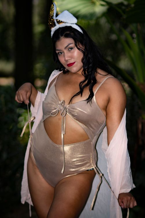 Free Striking portrait of a confident woman in a golden swimsuit posing outdoors. Stock Photo
