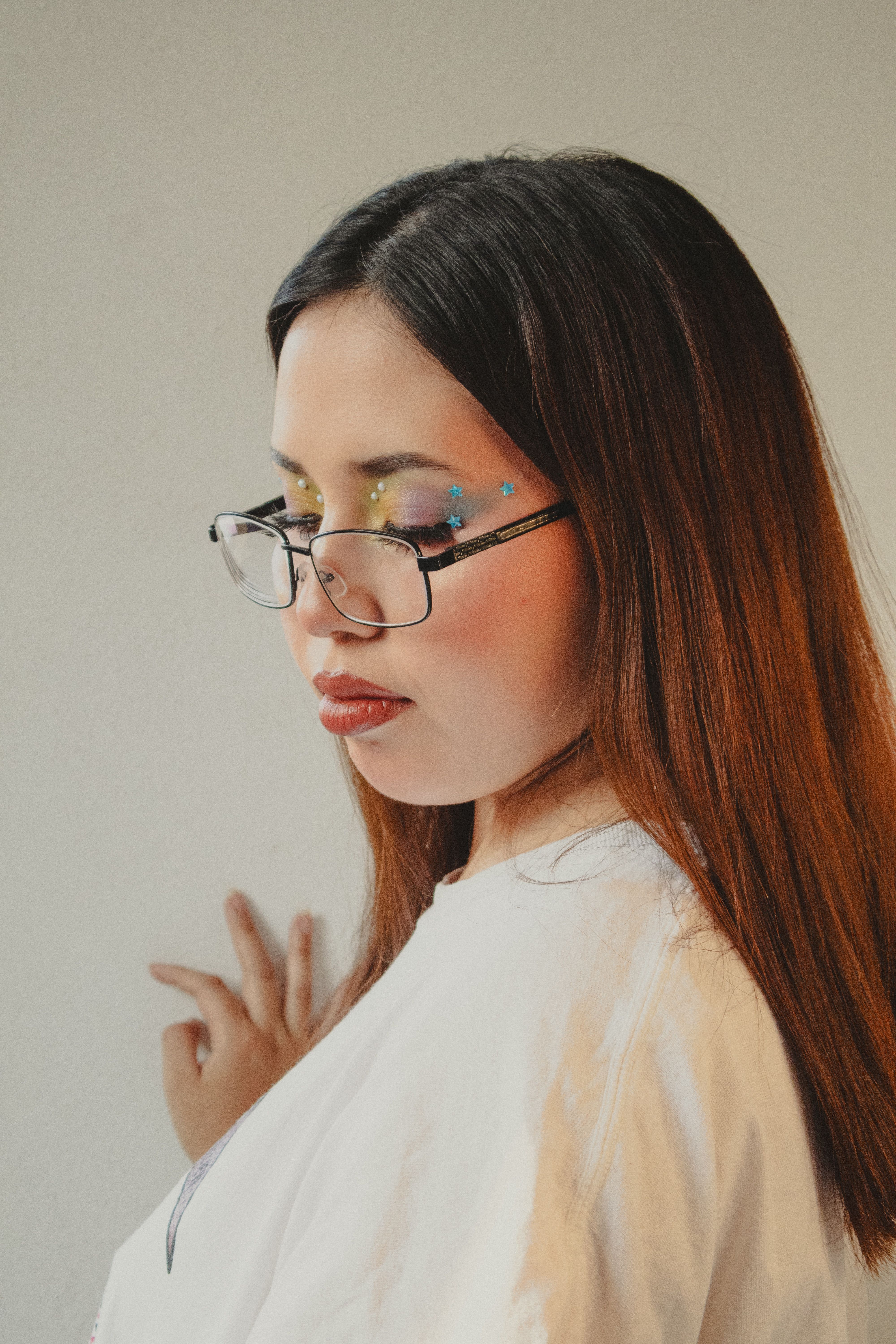 Close-up of a young woman with glasses and creative makeup art. Personal expression and style.