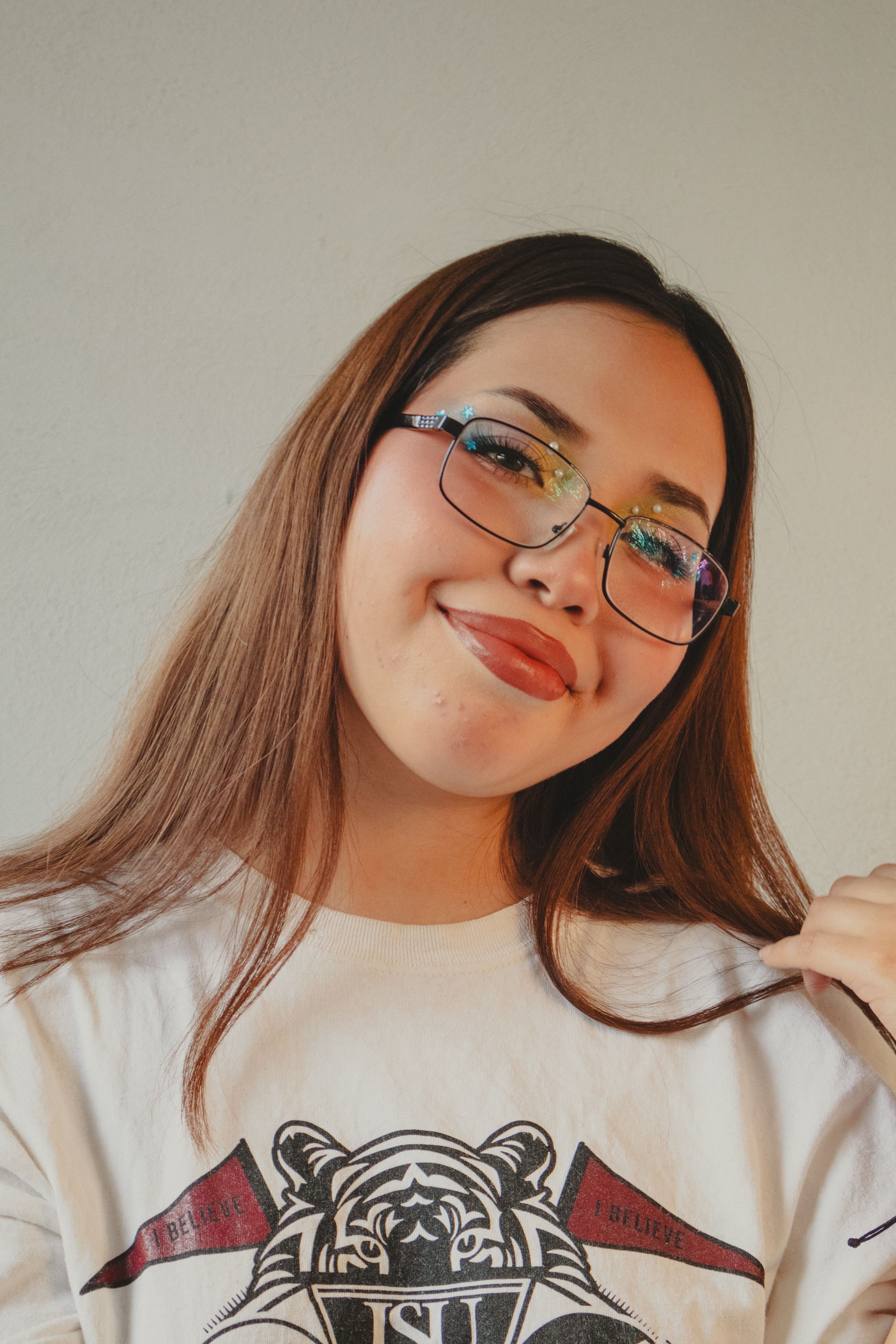 Young woman with glasses smiles confidently, creating a warm and engaging portrait.