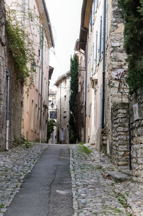 Free Discover a quaint cobblestone street lined with historic buildings in Vaison-la-Romaine, France. Stock Photo