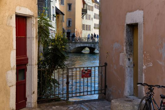 Picturesque canal scene in Annecy's historic district with a stone bridge and colorful buildings.