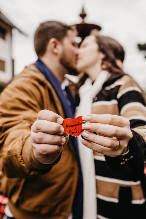 Man and Woman Kissing While Holding Heart Ornament